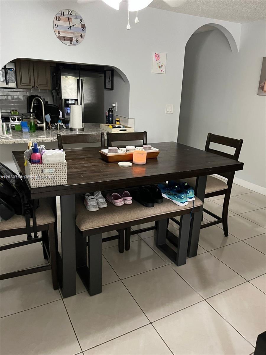 A dining area features a dark wood table with a bench, chairs, and kitchen access — 10135 NW 9th St Cir # 208, Miami FL 33172, MIAMI, FL