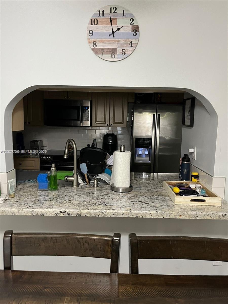 A kitchen with granite countertops and stainless steel appliances is viewed over a breakfast bar — 10135 NW 9th St Cir # 208, Miami FL 33172, MIAMI, FL