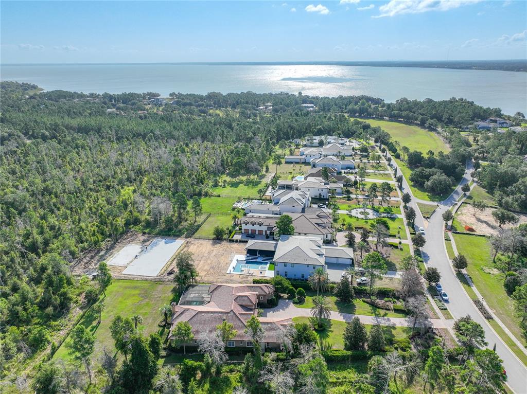 An aerial view shows several large houses with swimming pools situated near a large lake — 16028 PENDIO DRIVE, MONTVERDE, FL