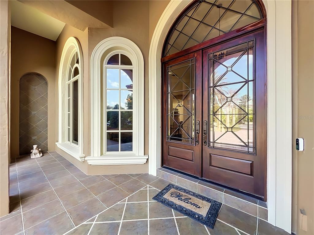 An arched double door entrance features glass panels, decorative molding, and tiled flooring — 16028 PENDIO DRIVE, MONTVERDE, FL