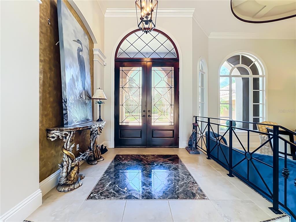 An entryway features a dark wood double door, a marble inlay floor, and decorative furniture — 16028 PENDIO DRIVE, MONTVERDE, FL