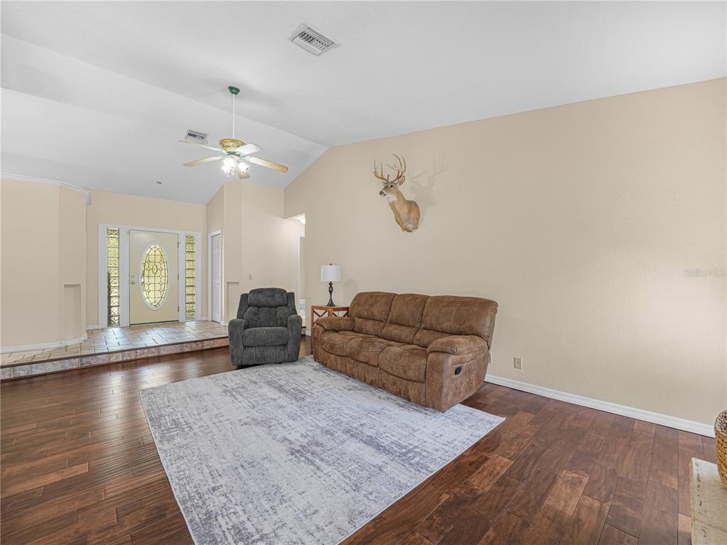 A living room features dark wood flooring, a brown sofa, a recliner, and a deer mount — 3437 MAR LISA COVE ROAD, LAKE WALES, FL