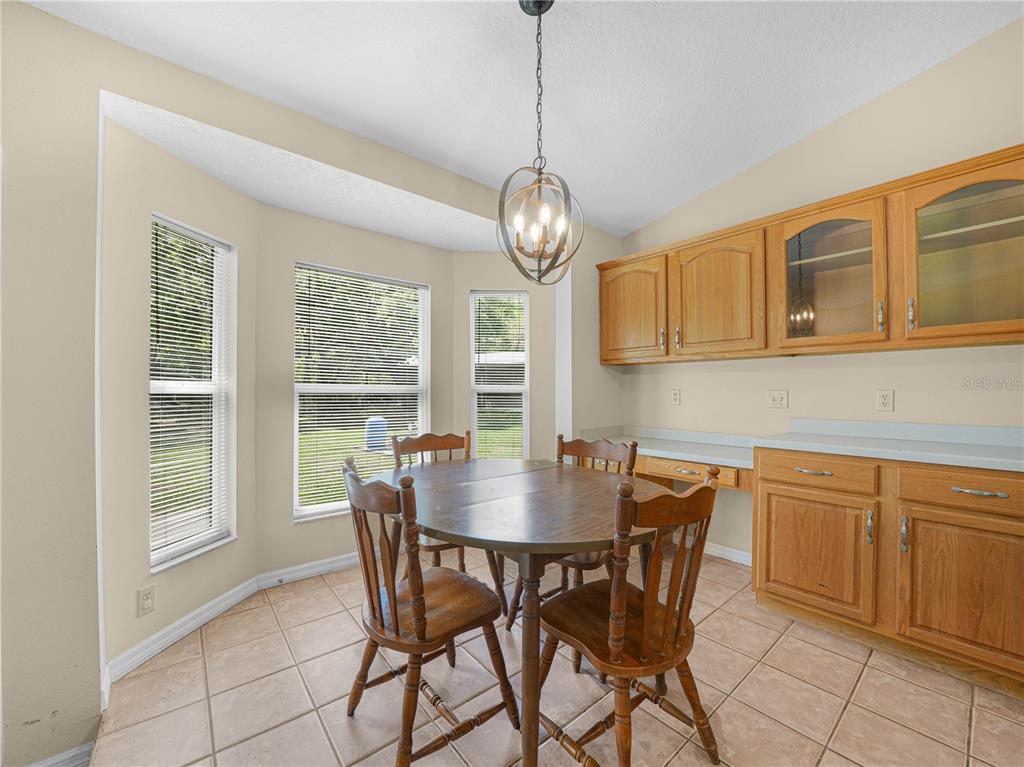 A dining area features a wooden table, chairs, tile flooring, and light oak cabinetry — 3437 MAR LISA COVE ROAD, LAKE WALES, FL