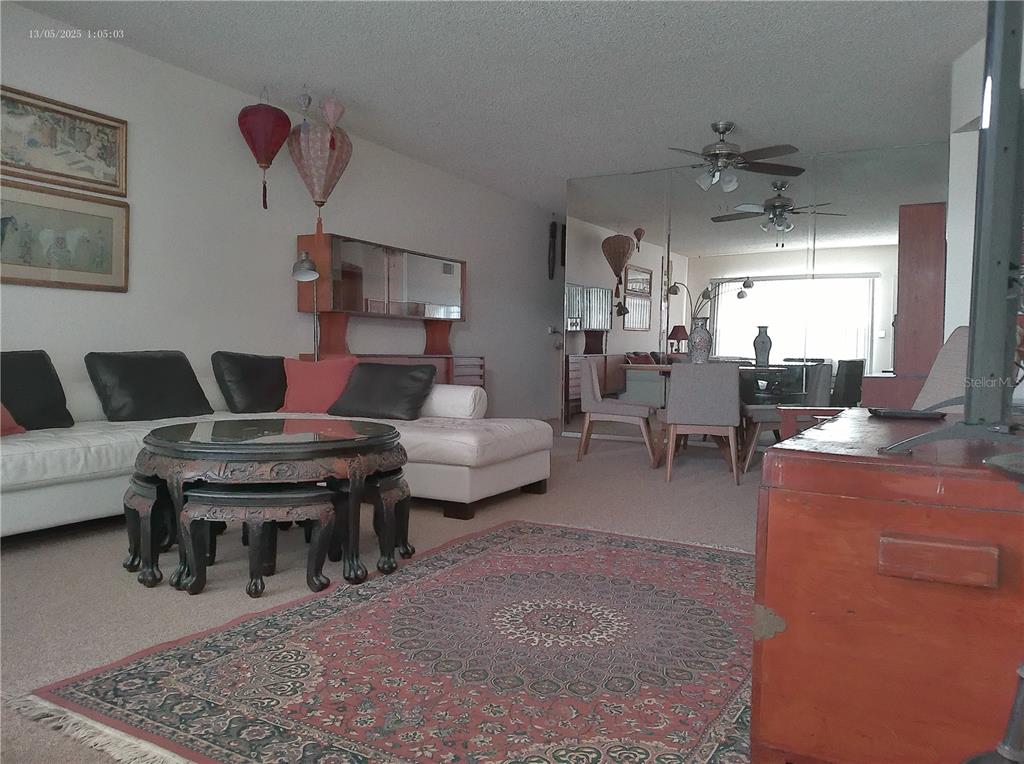 A living room features a white sectional sofa, a round carved table, and mirrored walls — 2361 ECUADORIAN WAY UNIT 45, CLEARWATER, FL