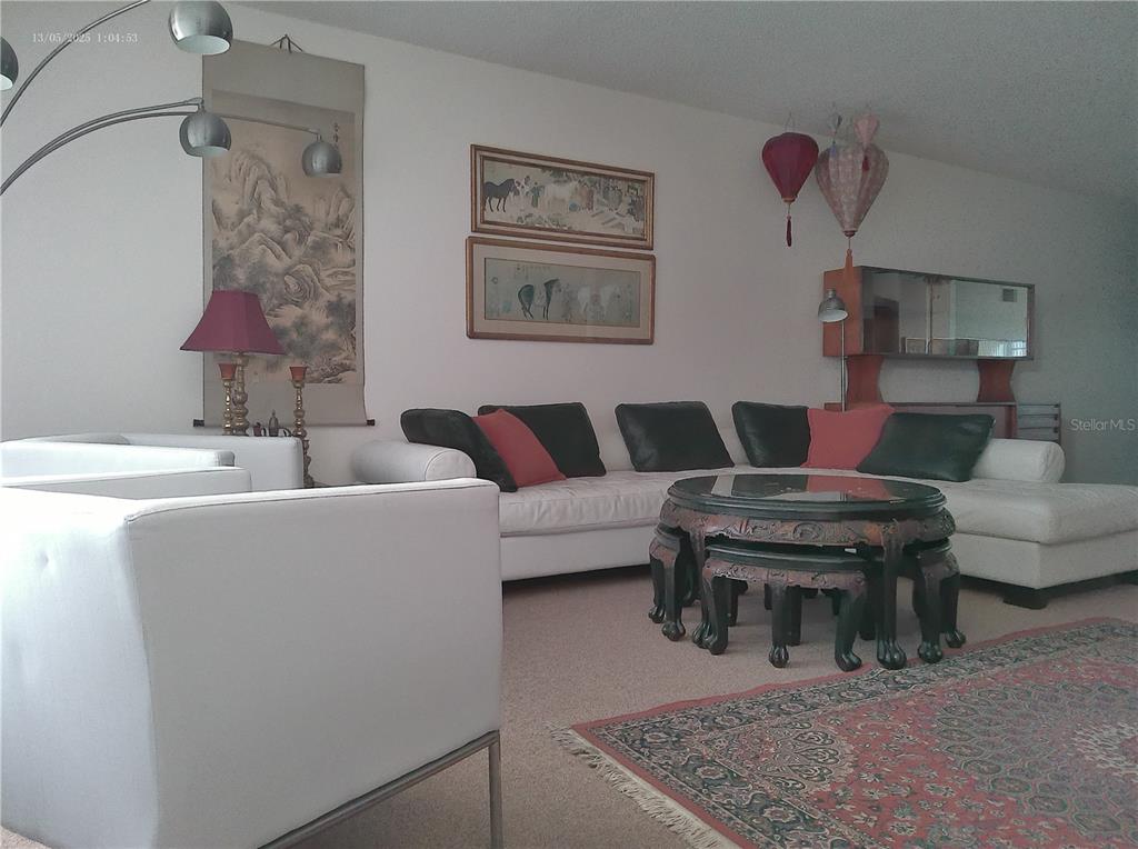 A living room features a white sectional sofa, a round carved table, and Asian-inspired decor — 2361 ECUADORIAN WAY UNIT 45, CLEARWATER, FL