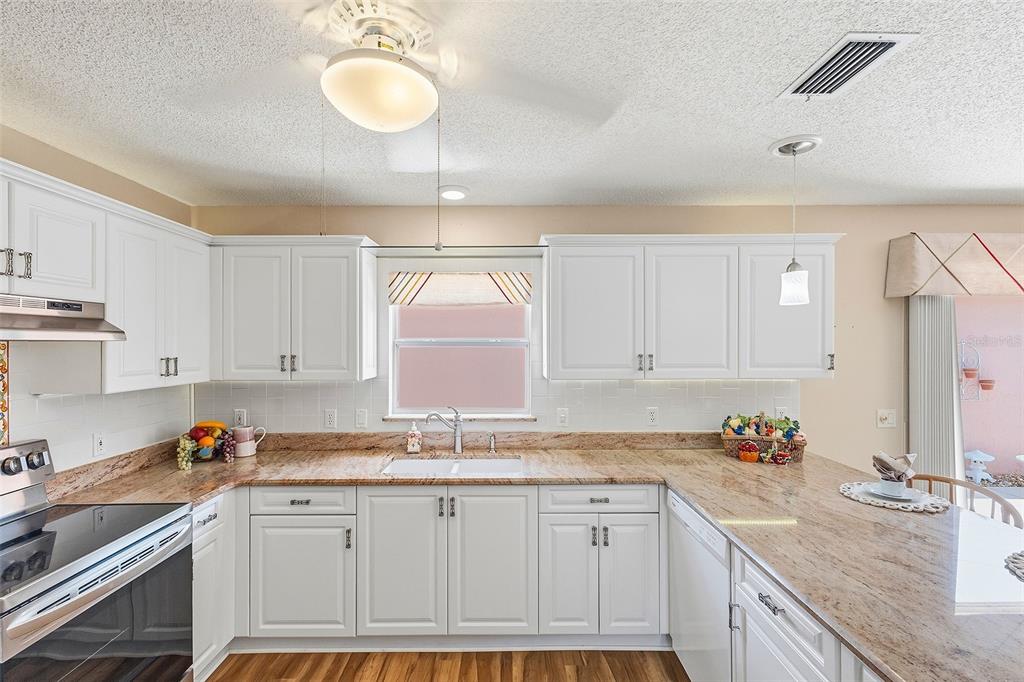 A kitchen features white cabinets, granite countertops, a double sink, and a ceiling fan — 867 OVIEDO ROAD, LADY LAKE, FL