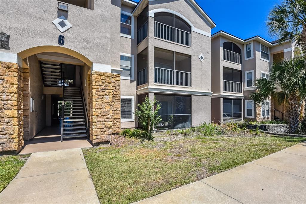 A stone-accented apartment building entrance features a central staircase leading to upper-level units — 940 VILLAGE TRAIL UNIT 6-103, PORT ORANGE, FL