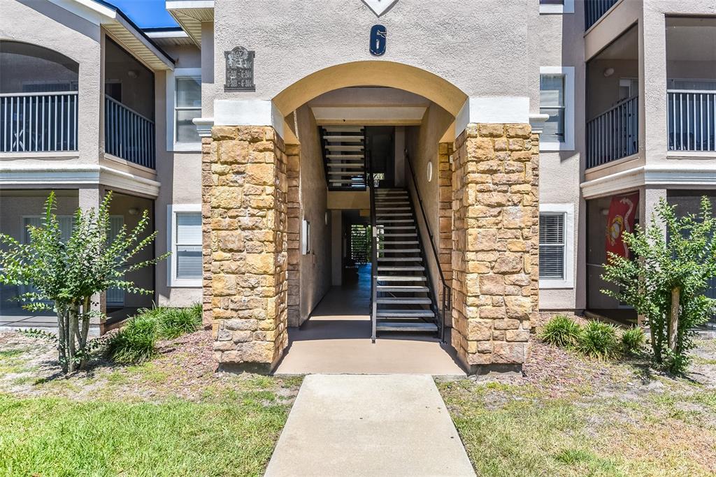 A stone entrance sign for Villaggio on the Lakes stands before a paved roundabout — 940 VILLAGE TRAIL UNIT 6-103, PORT ORANGE, FL