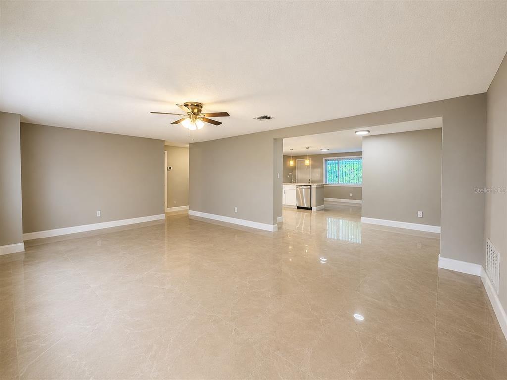 An open-concept living area features light-colored tile flooring, neutral walls, and a ceiling fan — 5419 DENVER STREET NE, ST PETERSBURG, FL