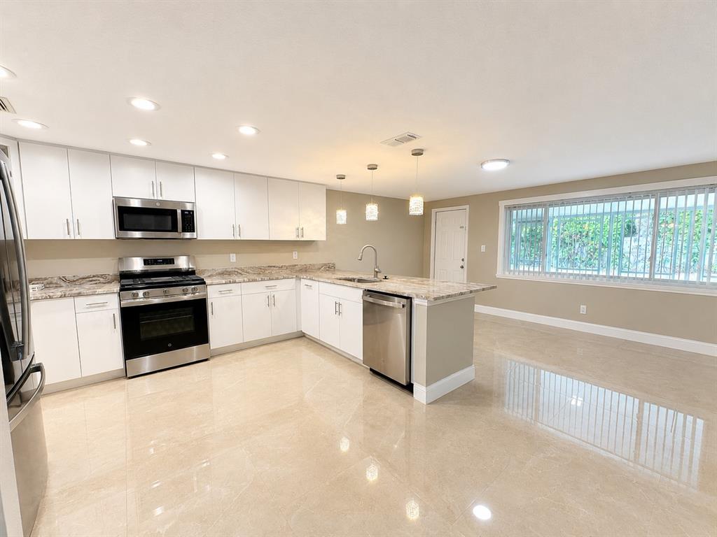 A kitchen with white cabinets, stainless steel appliances, and light-colored tile flooring — 5419 DENVER STREET NE, ST PETERSBURG, FL