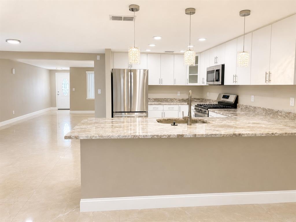 A kitchen with white cabinets, stainless steel appliances, and a granite-topped island — 5419 DENVER STREET NE, ST PETERSBURG, FL