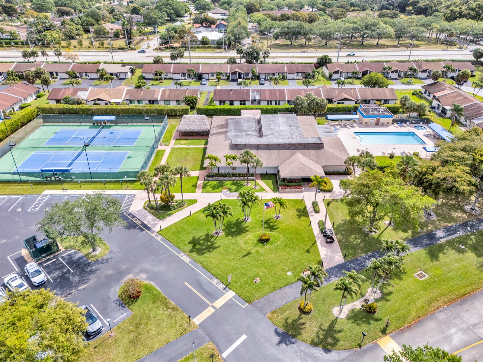 An aerial view shows a community clubhouse with a swimming pool and tennis courts — 5190 Las Verdes Circle # 315, Delray Beach FL 33484, DELRAY BEACH, FL