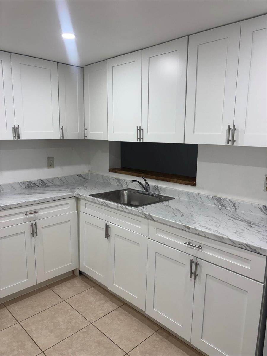 A kitchen features white shaker cabinets, marble-patterned laminate countertops, and a stainless steel sink — 5190 Las Verdes Circle # 315, Delray Beach FL 33484, DELRAY BEACH, FL