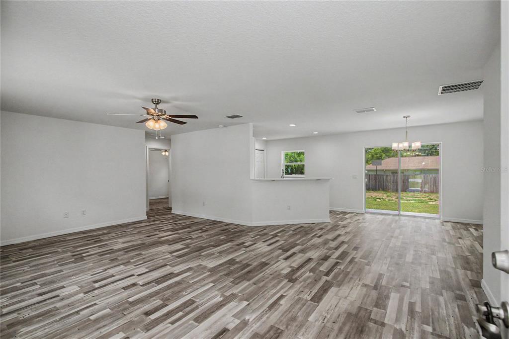 An open-concept living and dining area features white walls and gray wood-look flooring — 6197 NW 61ST STREET, OCALA, FL