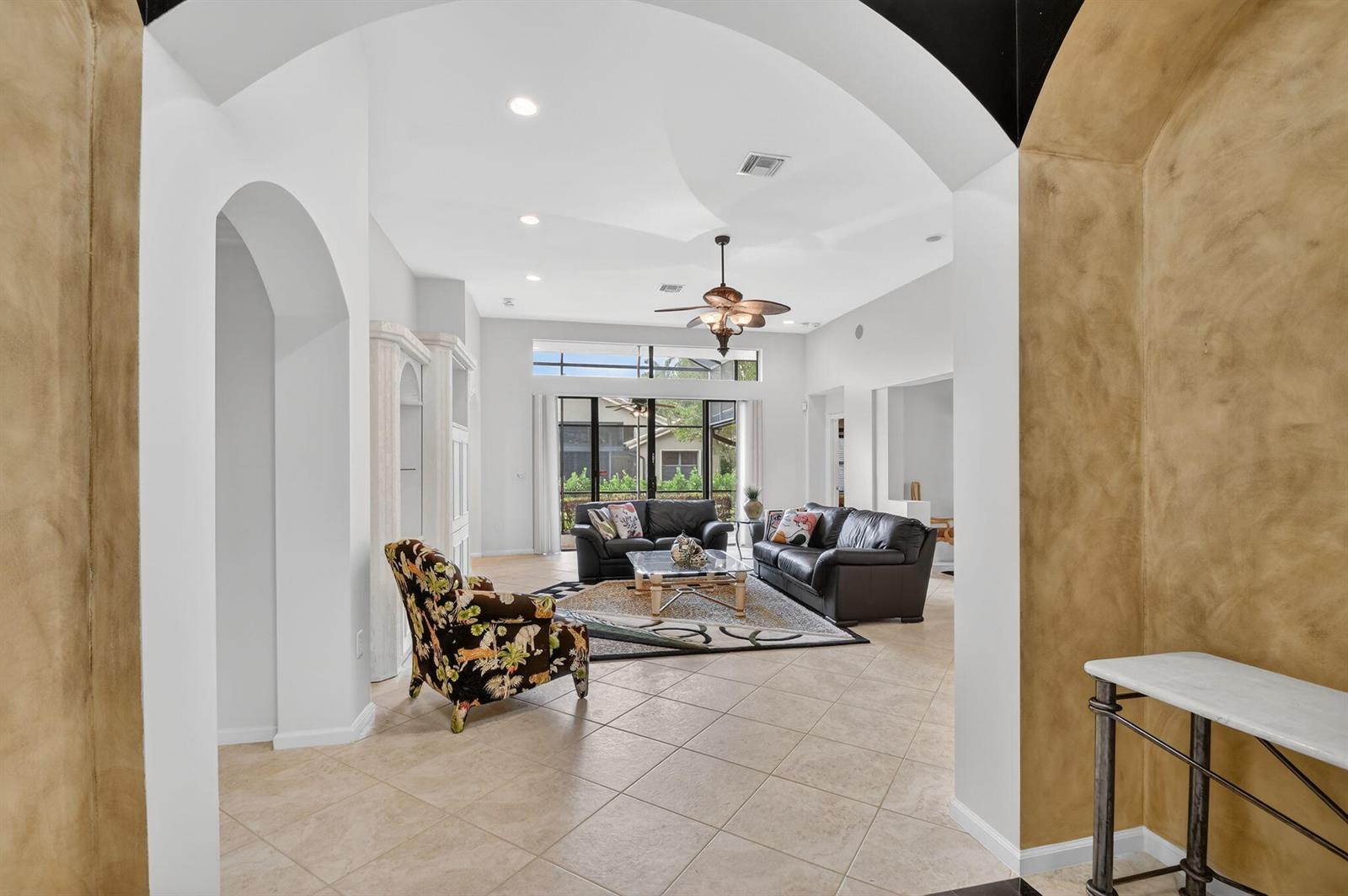 A living room with tile floors, leather sofas, and a patterned armchair under a ceiling fan — 8046 Via Grande, Boynton Beach FL 33437, BOYNTON BEACH, FL