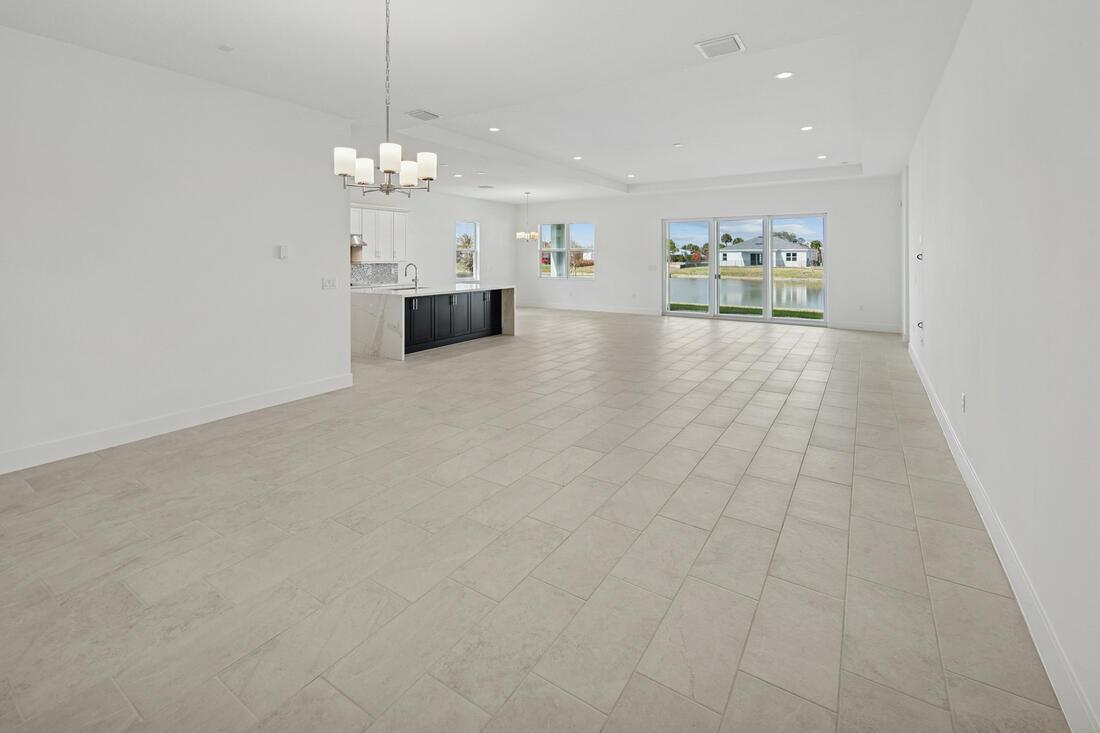An open-concept living area features light tile flooring, a kitchen island, and sliding glass doors — 2810 68th Street, Vero Beach FL 32967, VERO BEACH, FL