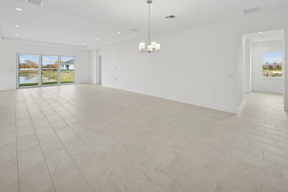 A spacious, empty room with white walls, light tile flooring, and a sliding glass door — 2810 68th Street, Vero Beach FL 32967, VERO BEACH, FL
