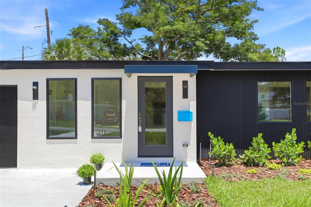 The exterior of a modern home features a white stucco wall, dark siding, and a door — 3006 NORTHWOOD BOULEVARD, WINTER PARK, FL