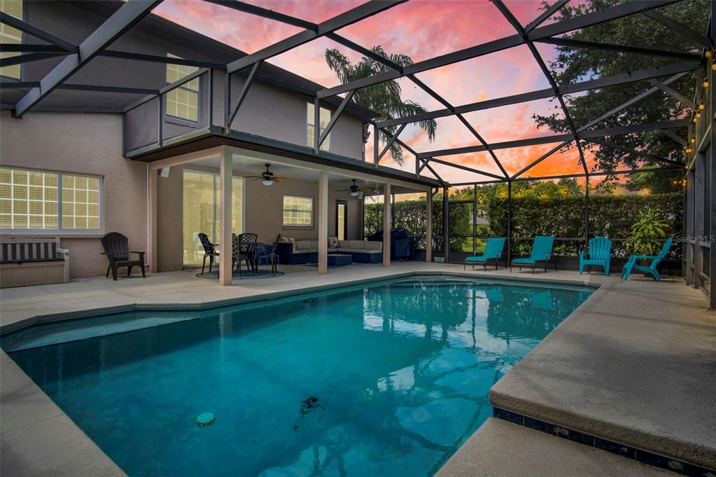 A swimming pool sits inside a screened-in lanai attached to the back of a house — 159 RED MAPLE BURL CIRCLE, DEBARY, FL