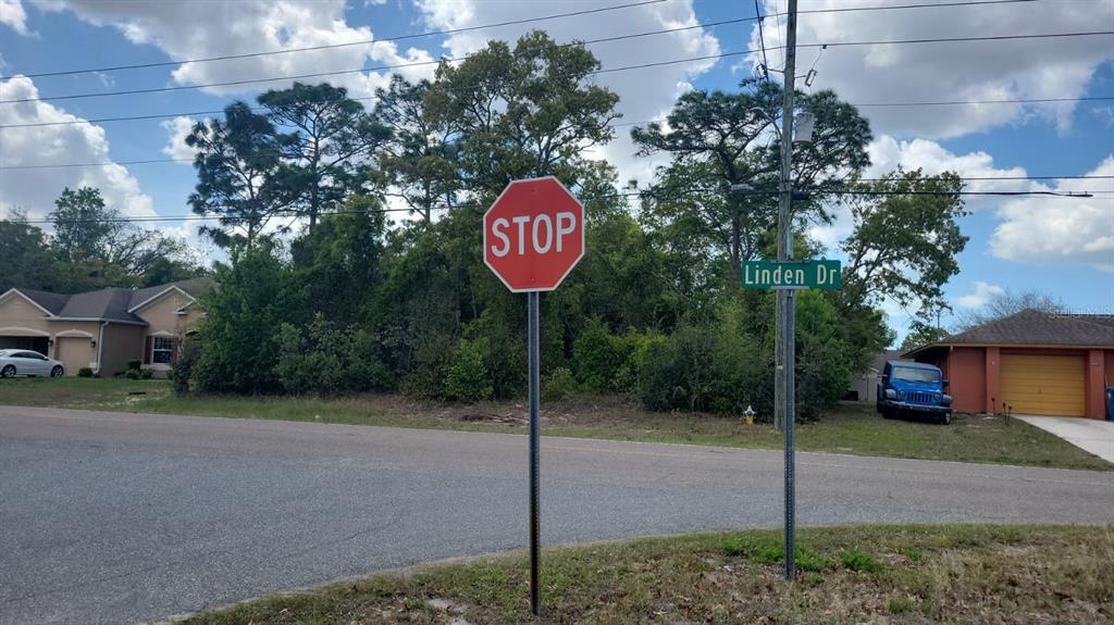 A stop sign and a street sign for Linden Dr stand in front of wooded lots — 12083 LINDEN DRIVE, SPRING HILL, FL