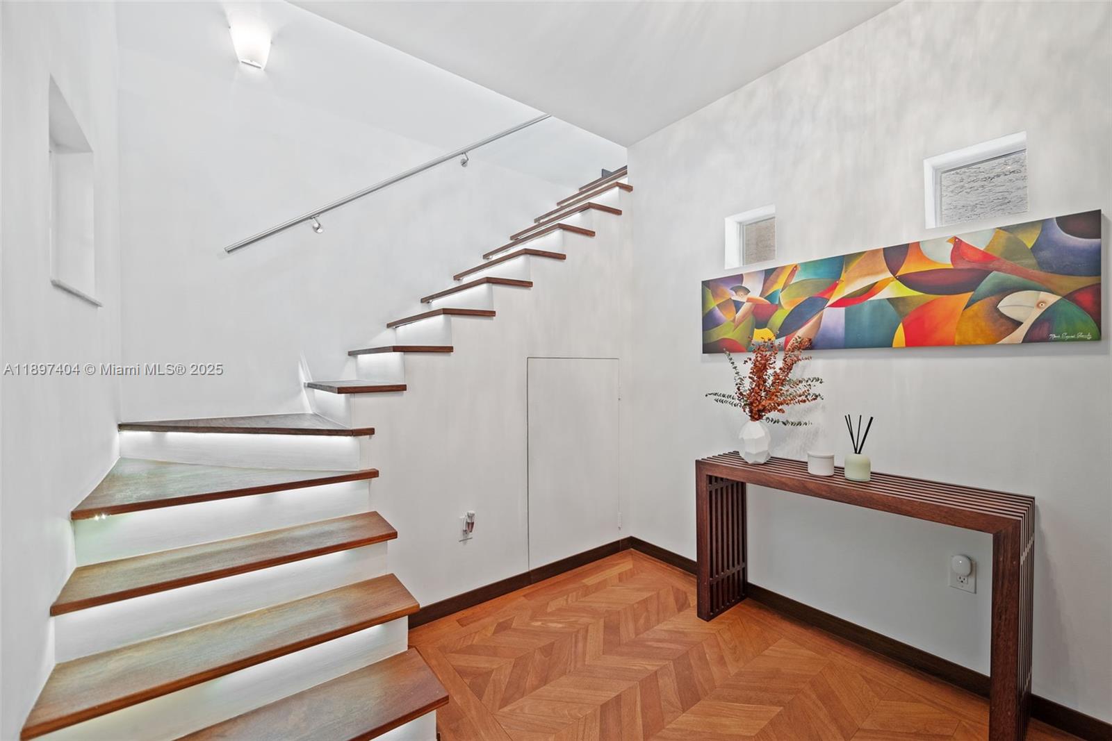A modern staircase with floating wooden treads and integrated lighting sits beside a console table — 261 Navarre Ave # 3, Coral Gables FL 33134, CORAL GABLES, FL