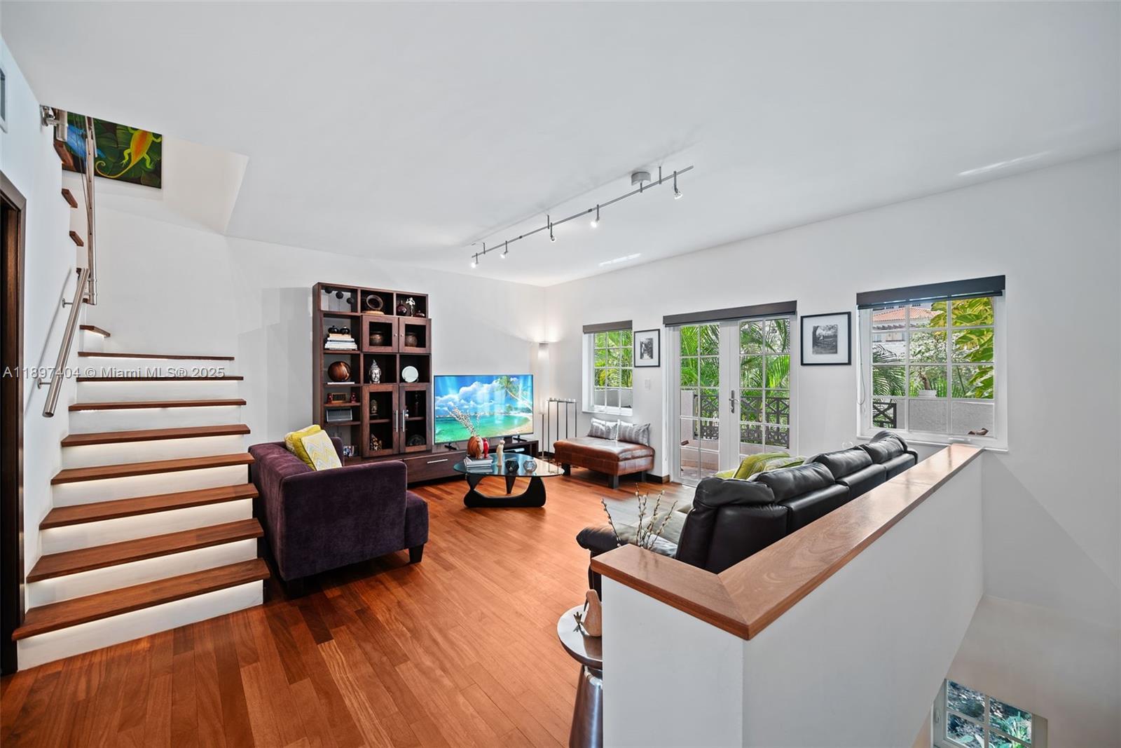 A living room features hardwood floors, a floating staircase, and a black leather sofa — 261 Navarre Ave # 3, Coral Gables FL 33134, CORAL GABLES, FL