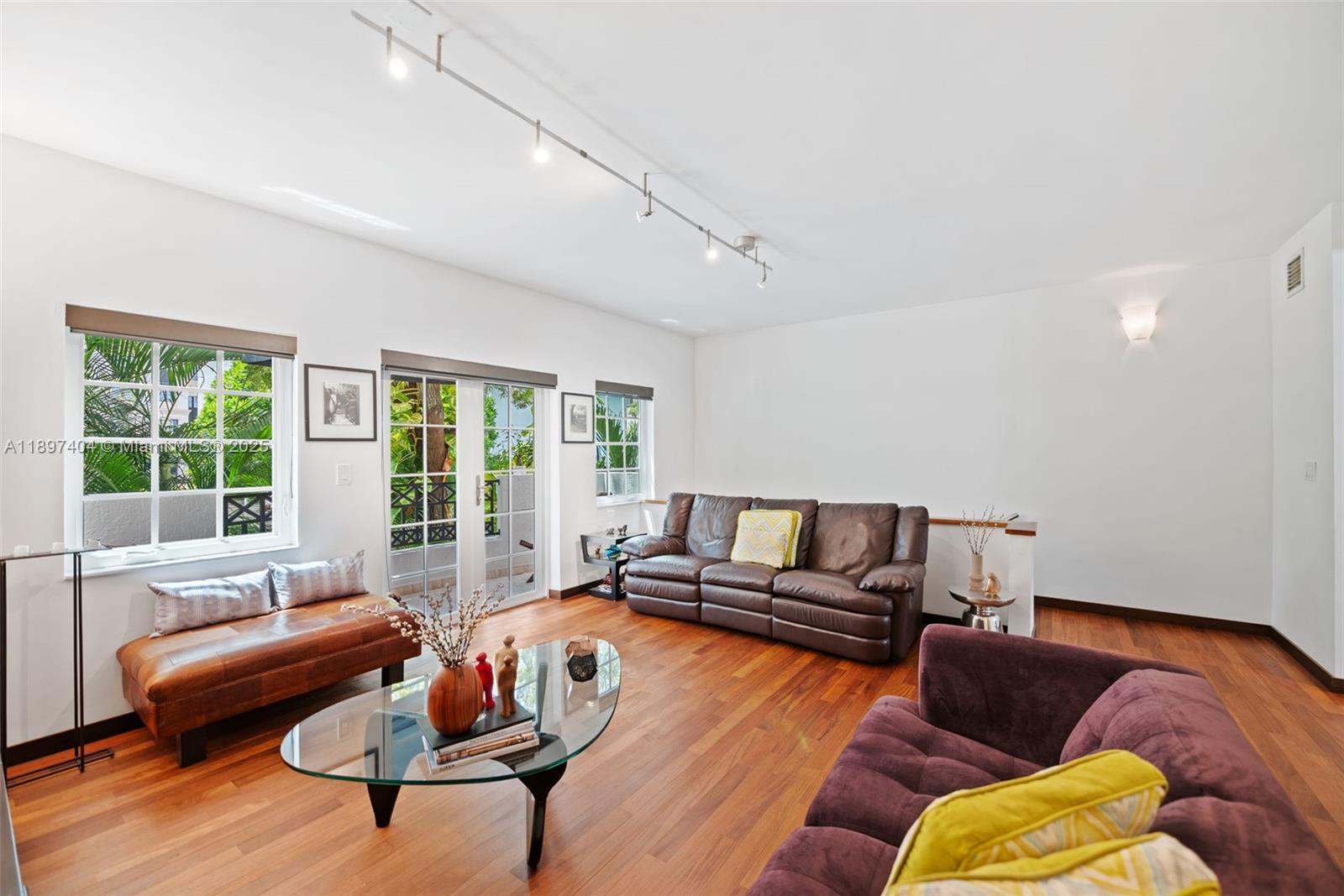 A living room features hardwood floors, a brown leather sofa, and a purple sofa — 261 Navarre Ave # 3, Coral Gables FL 33134, CORAL GABLES, FL