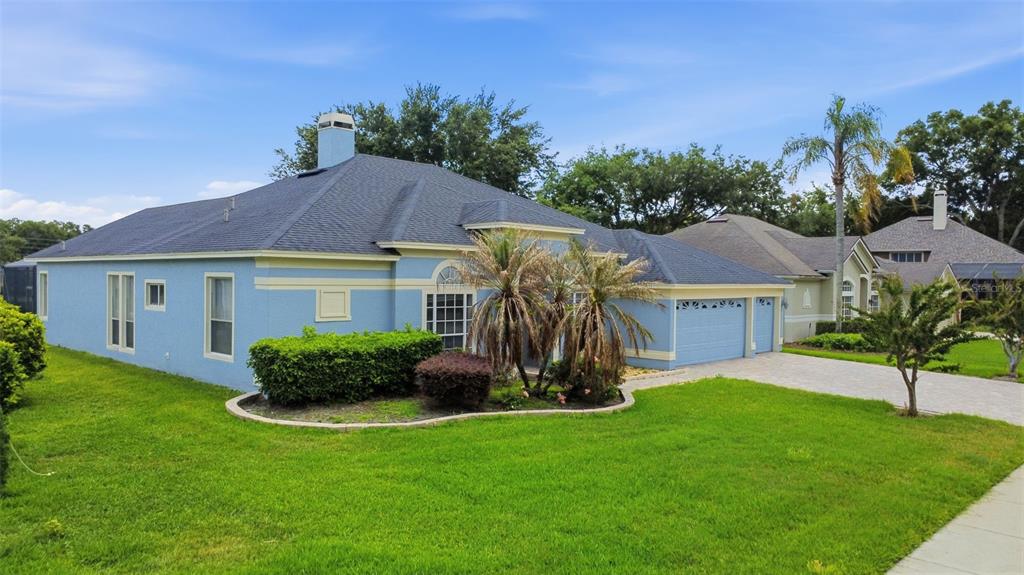 A blue single-story house with a dark shingled roof, a two-car garage, and front landscaping — 120 BLUE STONE CIRCLE, WINTER GARDEN, FL
