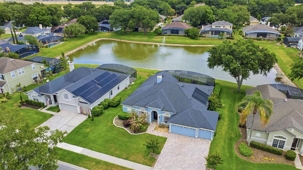 An aerial view shows suburban houses with swimming pool enclosures surrounding a central pond — 120 BLUE STONE CIRCLE, WINTER GARDEN, FL