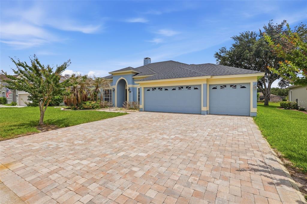 A single-story house with a blue exterior, yellow trim, and a paved driveway — 120 BLUE STONE CIRCLE, WINTER GARDEN, FL