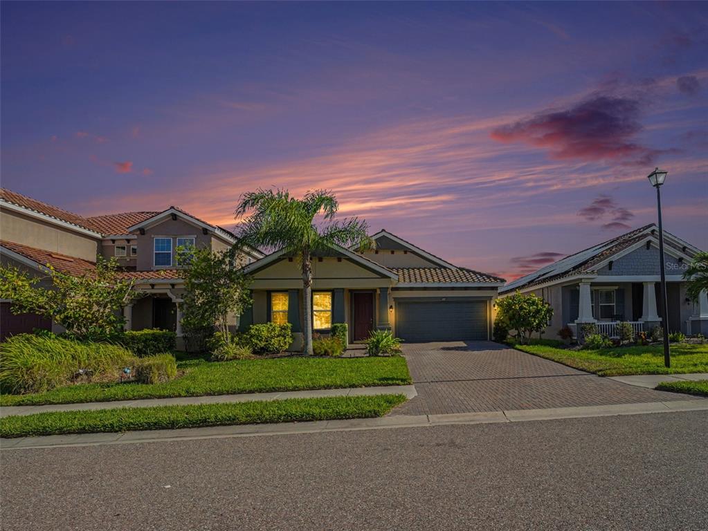 A single-story suburban house with a paved driveway and a palm tree at sunset — 4429 CONCHFISH LANE, OSPREY, FL