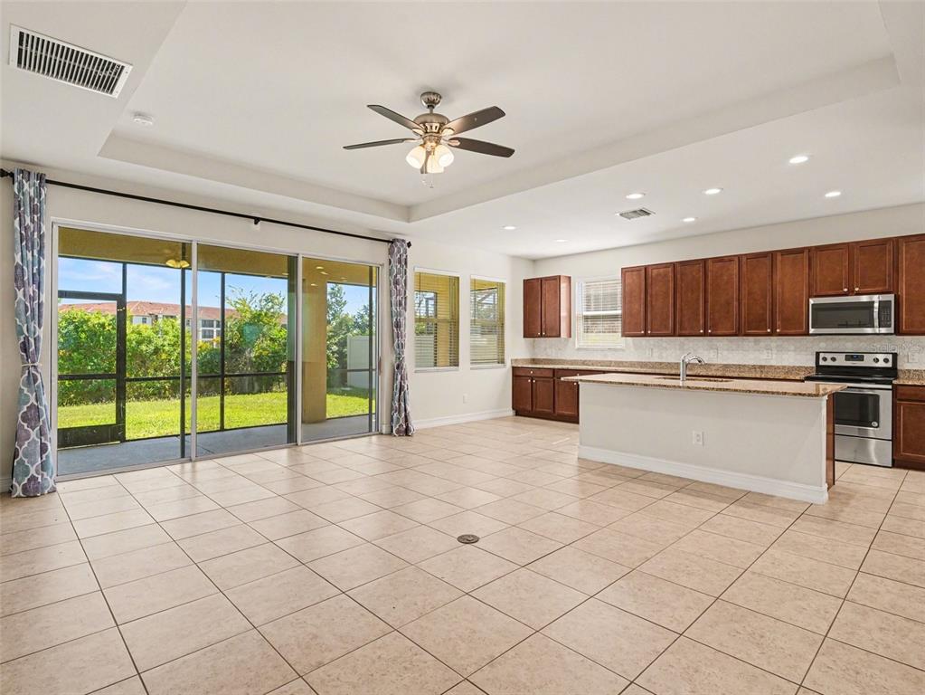 A spacious kitchen and living area with tile floors, dark wood cabinets, and sliding glass doors — 4429 CONCHFISH LANE, OSPREY, FL