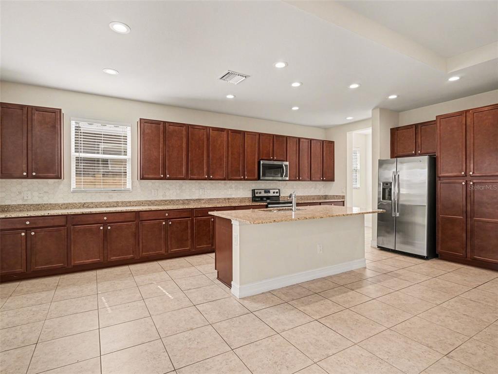A kitchen features dark wood cabinets, granite countertops, stainless steel appliances, and tile flooring — 4429 CONCHFISH LANE, OSPREY, FL