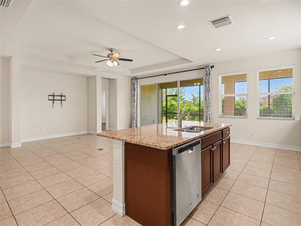 A kitchen island with a stainless steel dishwasher sits in an open-concept room with tile floors — 4429 CONCHFISH LANE, OSPREY, FL
