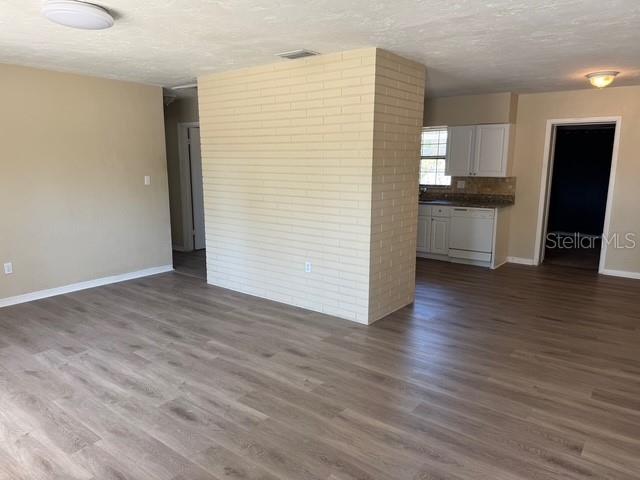 A living room with light-colored wood-look flooring features a central painted brick accent wall — 1415 WOOD AVENUE, CLEARWATER, FL