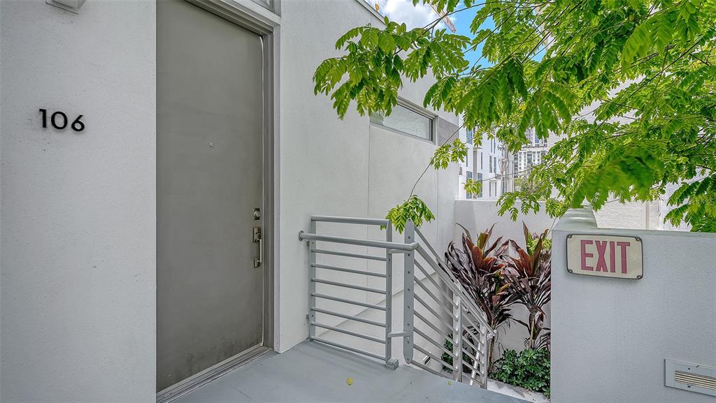 A gray door labeled 106 stands next to a metal staircase and an exit sign — 1350 5TH STREET UNIT 106, SARASOTA, FL