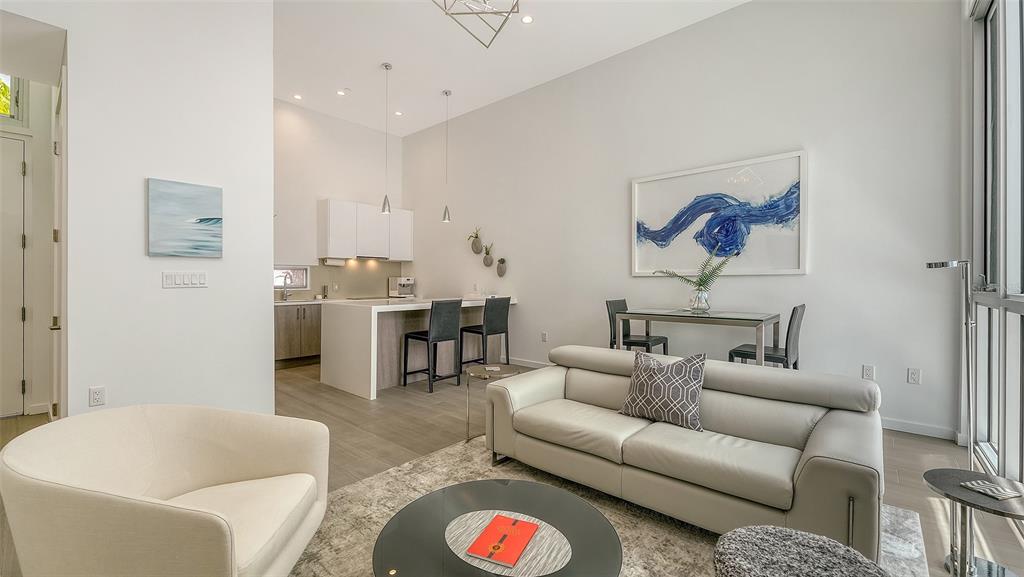 A modern open-concept living room features a white sofa, dining area, and kitchen island — 1350 5TH STREET UNIT 106, SARASOTA, FL