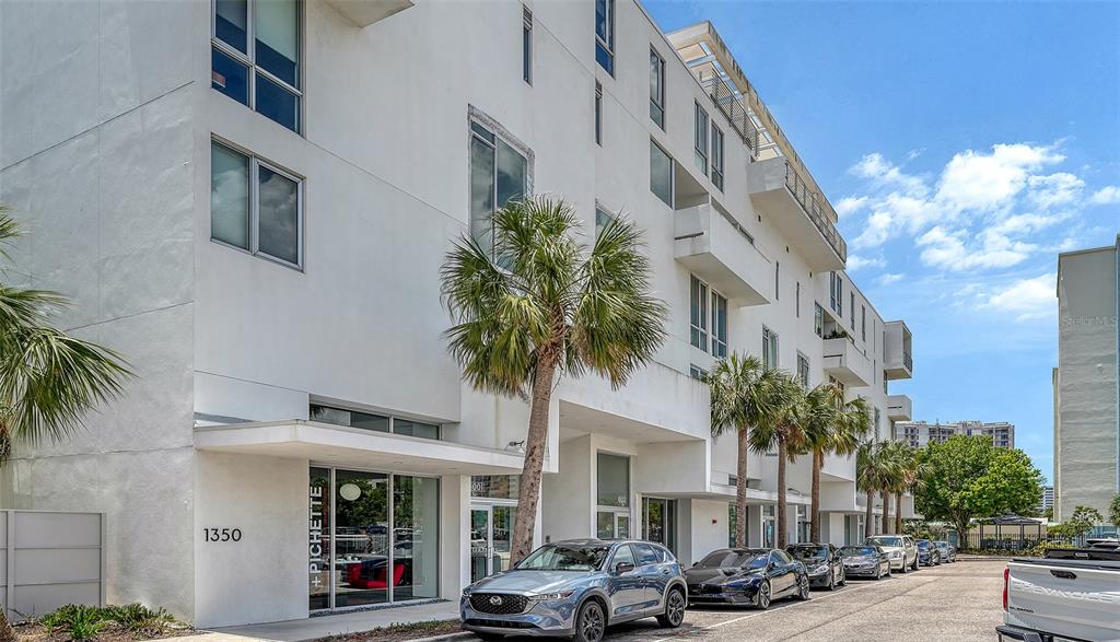 A modern white multi-story building with a street-level storefront and parked cars — 1350 5TH STREET UNIT 106, SARASOTA, FL