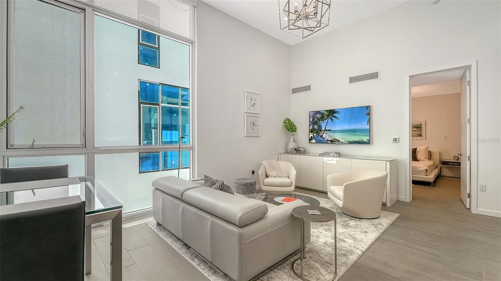 A modern living room features a grey sofa, two armchairs, and floor-to-ceiling windows — 1350 5TH STREET UNIT 106, SARASOTA, FL