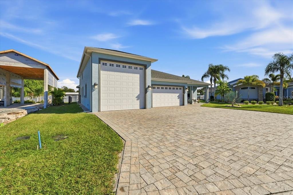 A light blue house features a large paver driveway and two separate garage doors — 149 LAYNEWADE ROAD, POLK CITY, FL