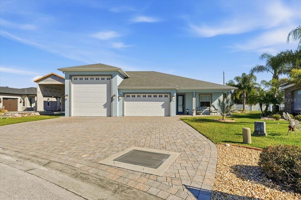 A light blue single-story house features a paver driveway and two white garage doors — 149 LAYNEWADE ROAD, POLK CITY, FL
