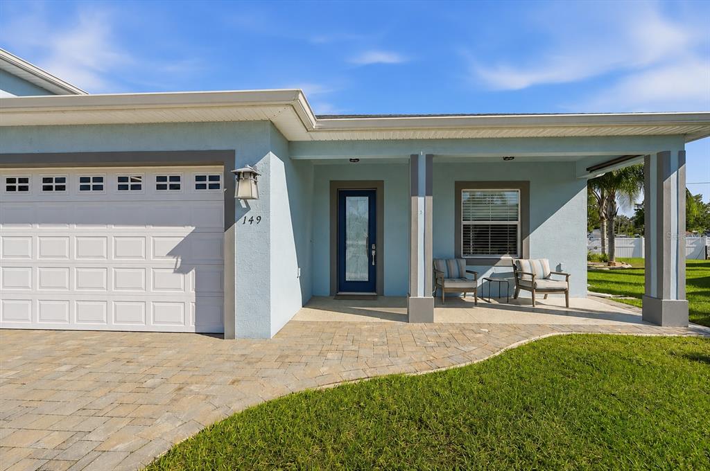 A light blue house exterior features a paved walkway, a garage, and a covered porch — 149 LAYNEWADE ROAD, POLK CITY, FL
