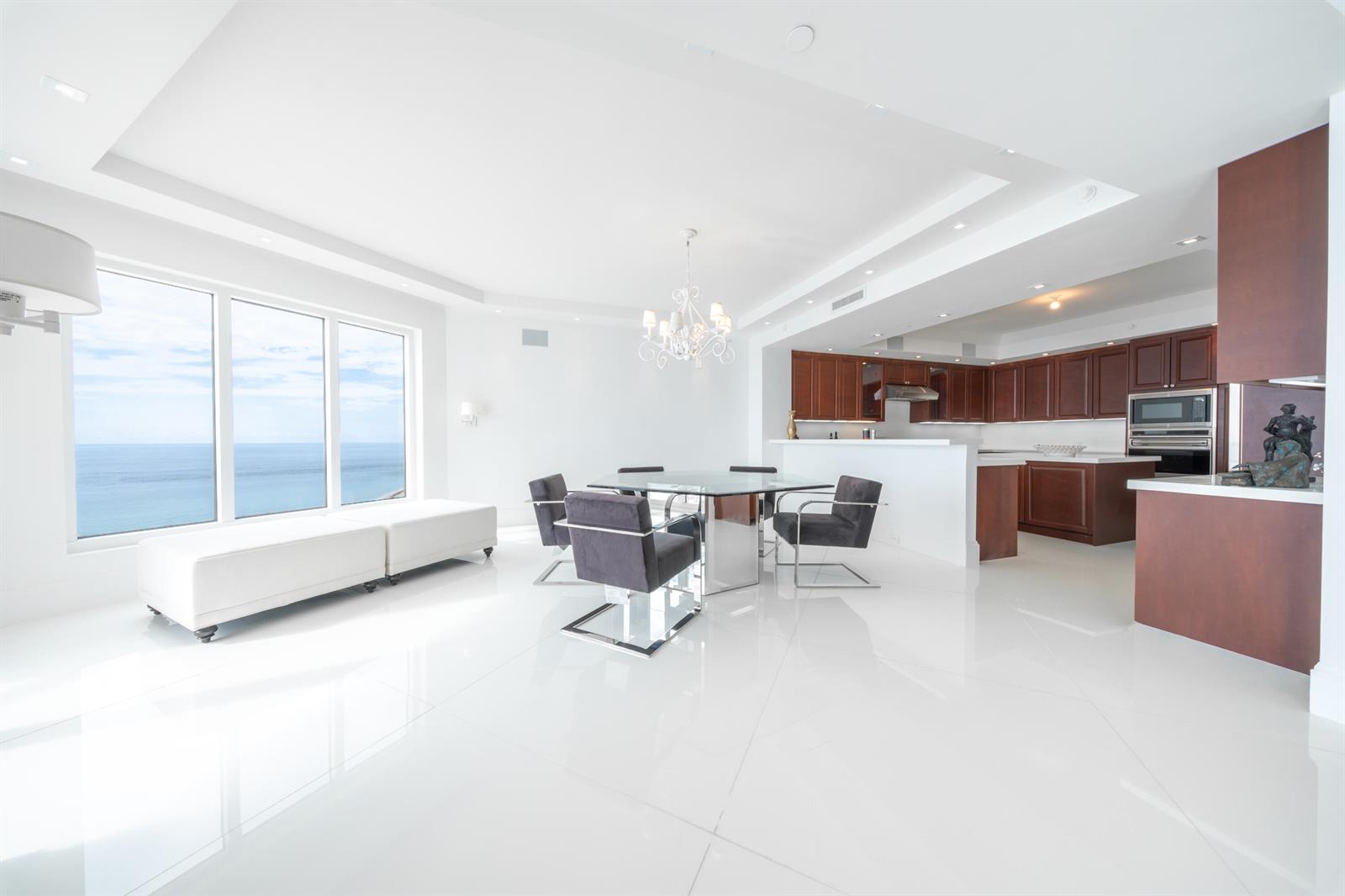 A modern dining area with white tile floors, a glass table, and ocean views — 2700 N Ocean Drive # 2501a, Riviera Beach FL 33404, RIVIERA BEACH, FL
