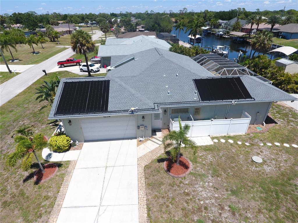 An aerial view shows a house with solar panels on the roof and a driveway — 4234 ROCK CREEK DRIVE, PORT CHARLOTTE, FL