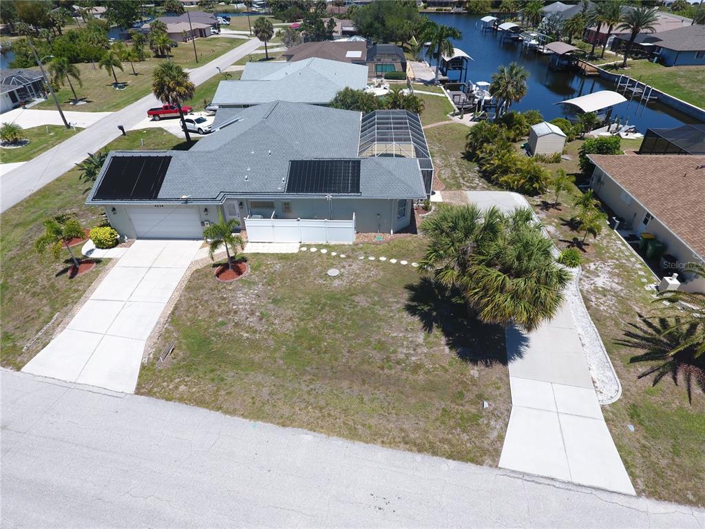 An aerial view shows a house with solar panels, a screened pool, and a canal — 4234 ROCK CREEK DRIVE, PORT CHARLOTTE, FL