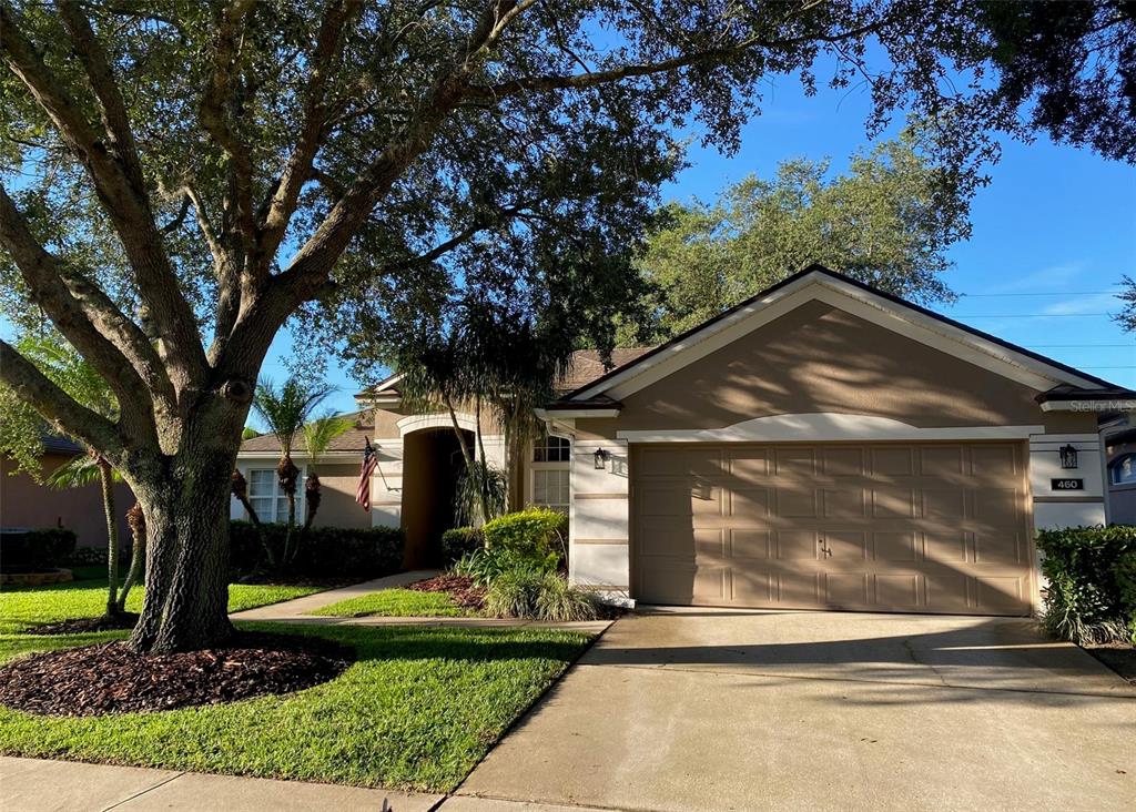 A tan single-story house with a two-car garage and a large tree in the yard — 460 PICKFAIR TERRACE, LAKE MARY, FL