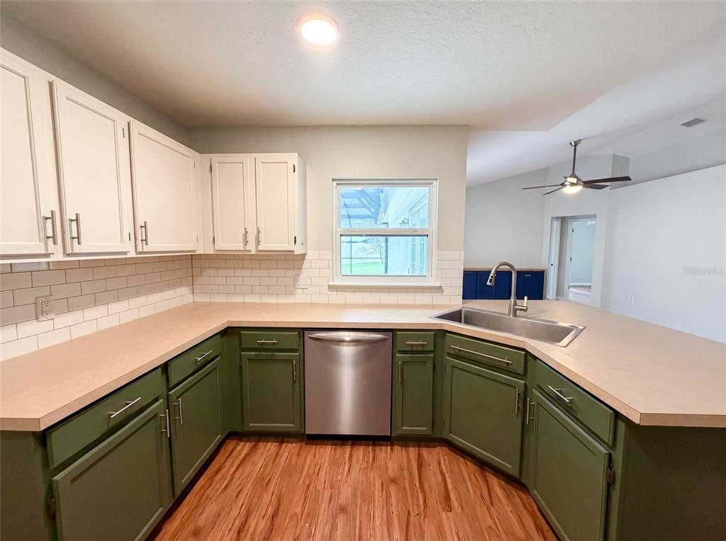 A kitchen features two-toned green and white cabinets, a stainless steel dishwasher, and laminate countertops — 546 PENNS NECK DRIVE, DELAND, FL