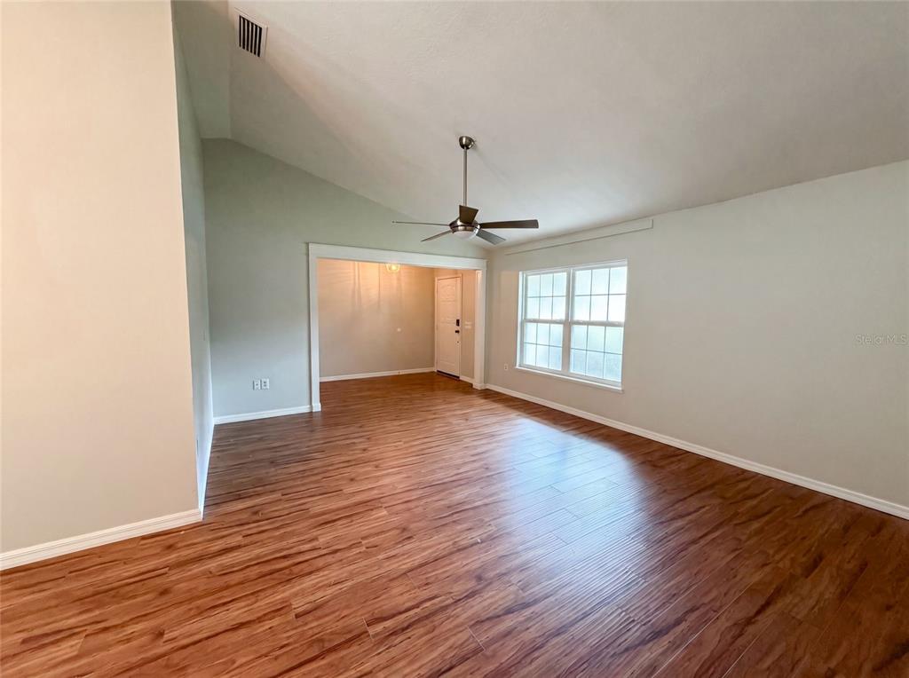 A living room with vaulted ceilings, wood-look flooring, and a ceiling fan — 546 PENNS NECK DRIVE, DELAND, FL