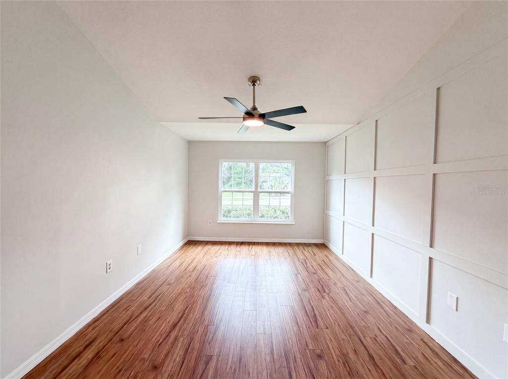 A room with wood-look flooring, a ceiling fan, and a paneled accent wall — 546 PENNS NECK DRIVE, DELAND, FL