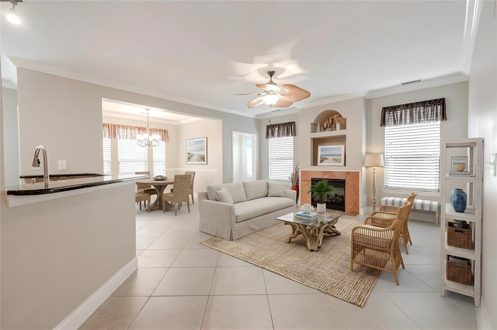 A living room with a fireplace, ceiling fan, and dining area on a tile floor — 2749 VIA CIPRIANI UNIT 1010B, CLEARWATER, FL